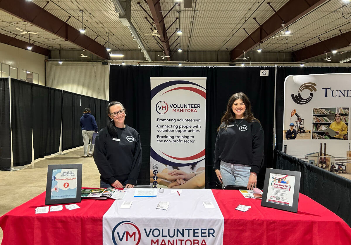 Volunteer Manitoba team members standing at a booth