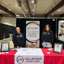 Volunteer Manitoba team members standing at a booth